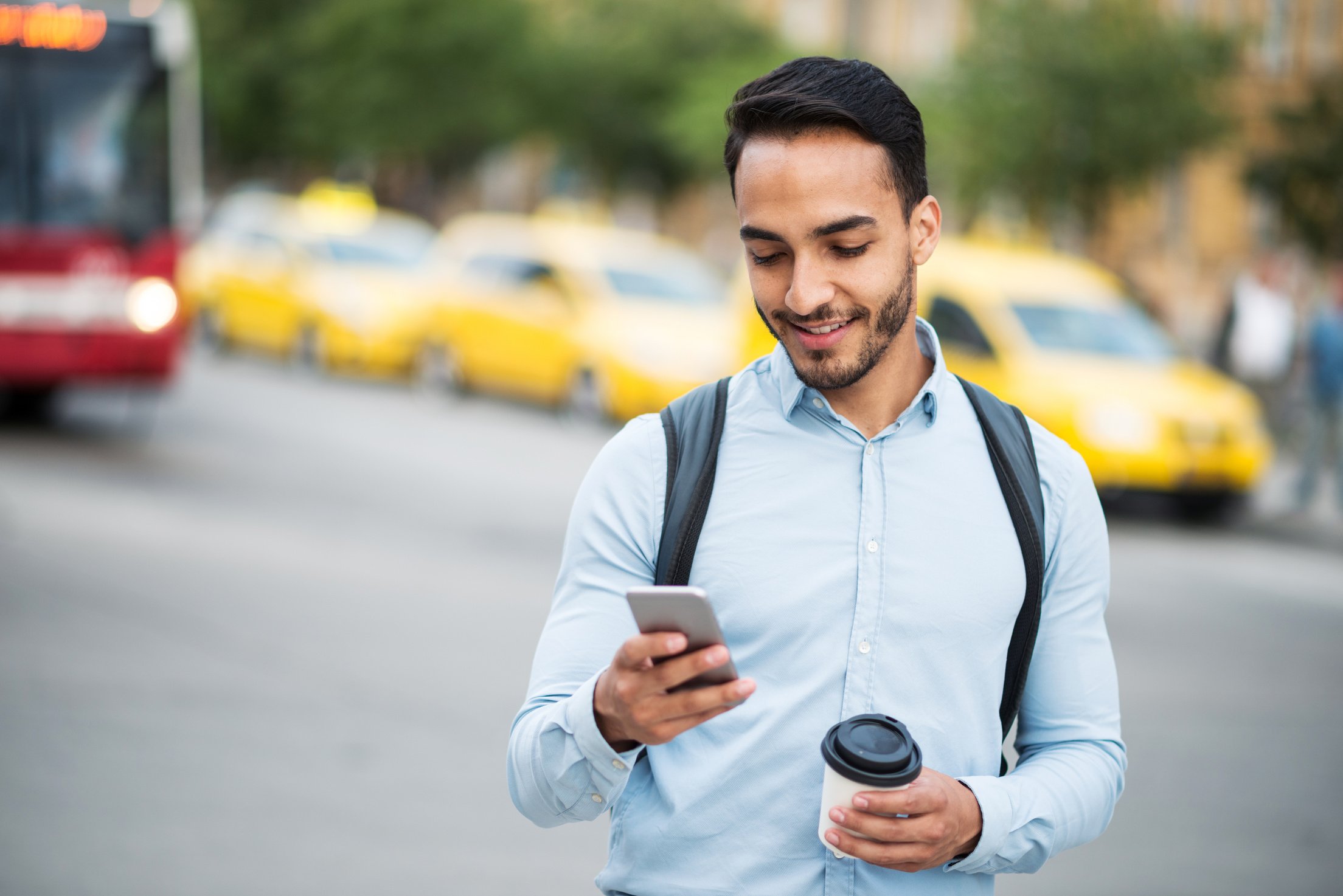 Latino man checking the bus timetable on mobile app